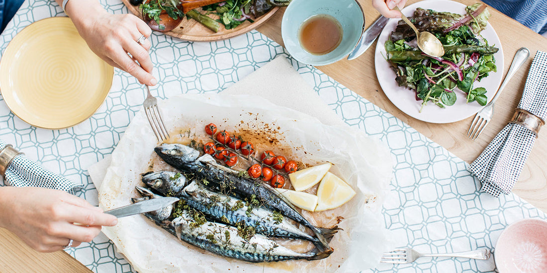 two people serving fish and salad