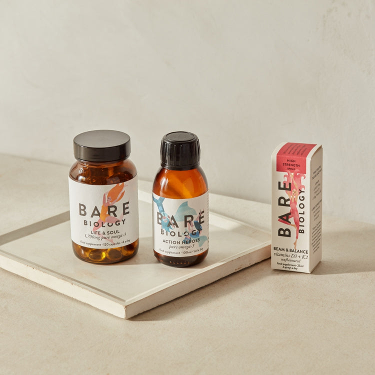 Bare Biology products including a bottle, a box, and a jar on a light surface with a neutral background.