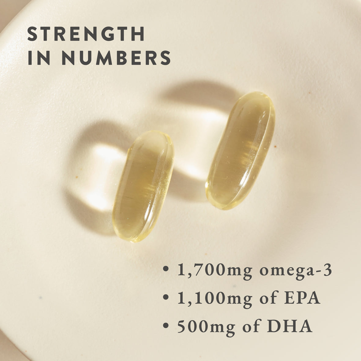 Two yellowish Bare Biology Life & Soul Omega-3 Fish Oil Daily Capsules rest on a white surface, with text: STRENGTH IN NUMBERS; 1,700mg Omega-3 for brain & heart health; 1,100mg EPA; 500mg DHA.