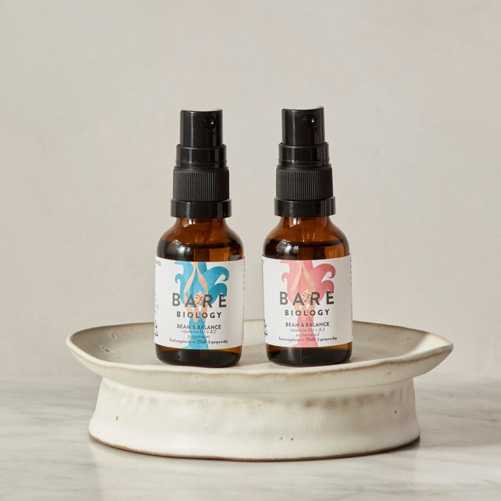 Woman holding bare biology's beam & balance vitamin d + k2 spray range