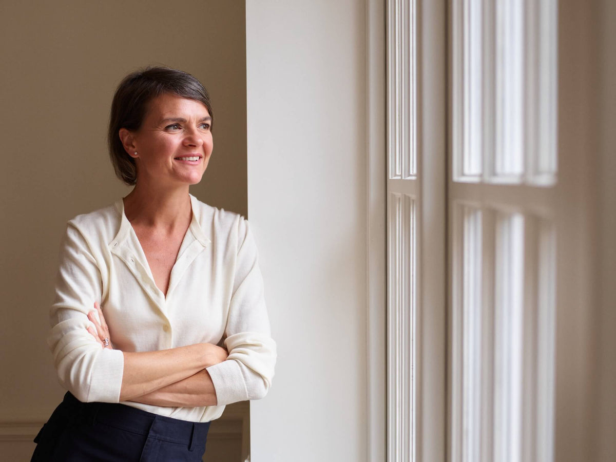 Stylish woman leant against a wall and looking out of the window