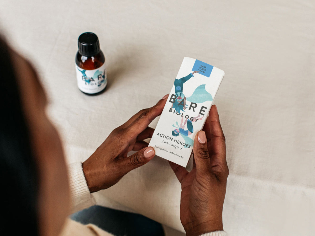 Person holding a 'Bare Biology' product with a bottle in the background
