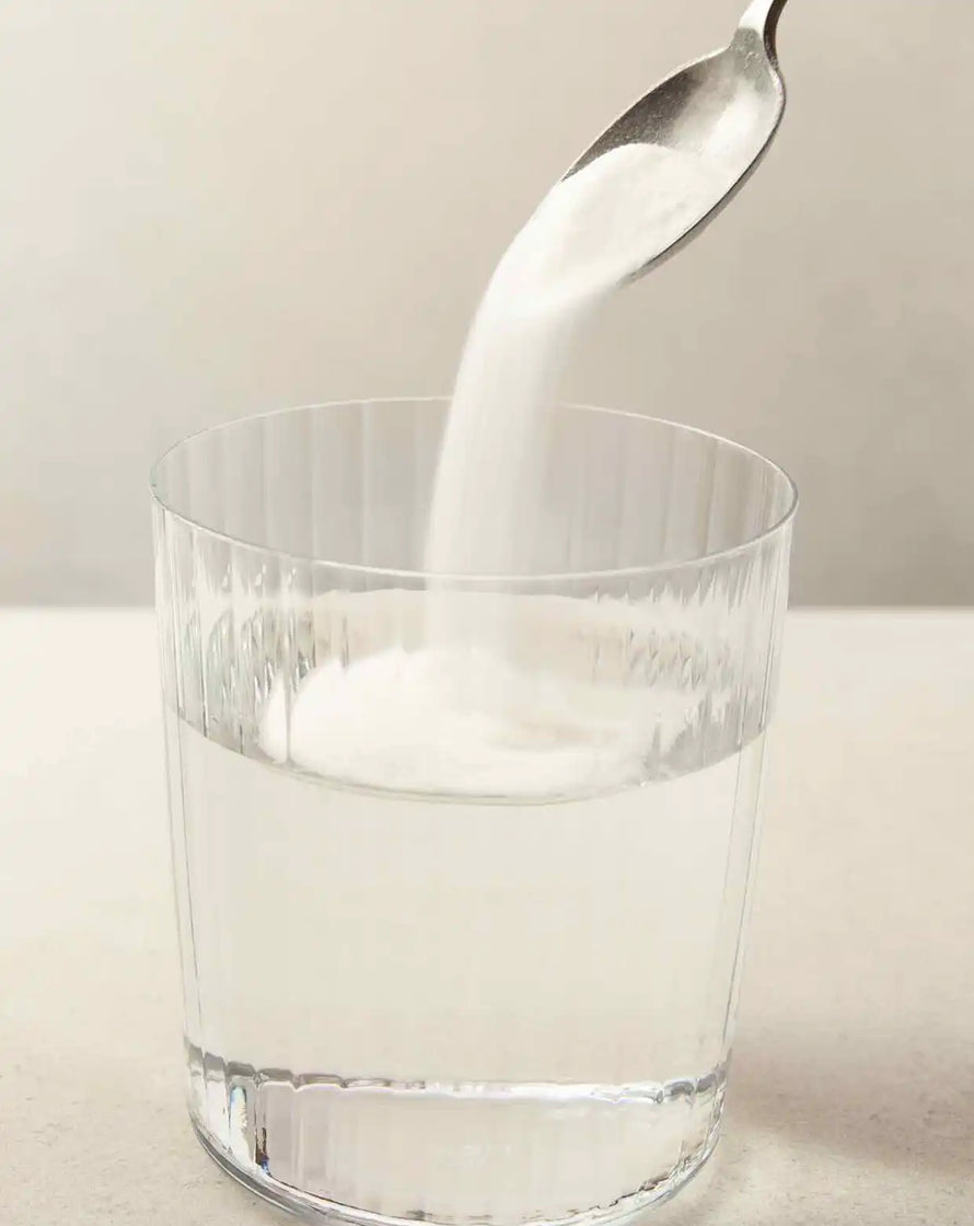 bare biology skinful marine collagen powder being poured into a glass of water