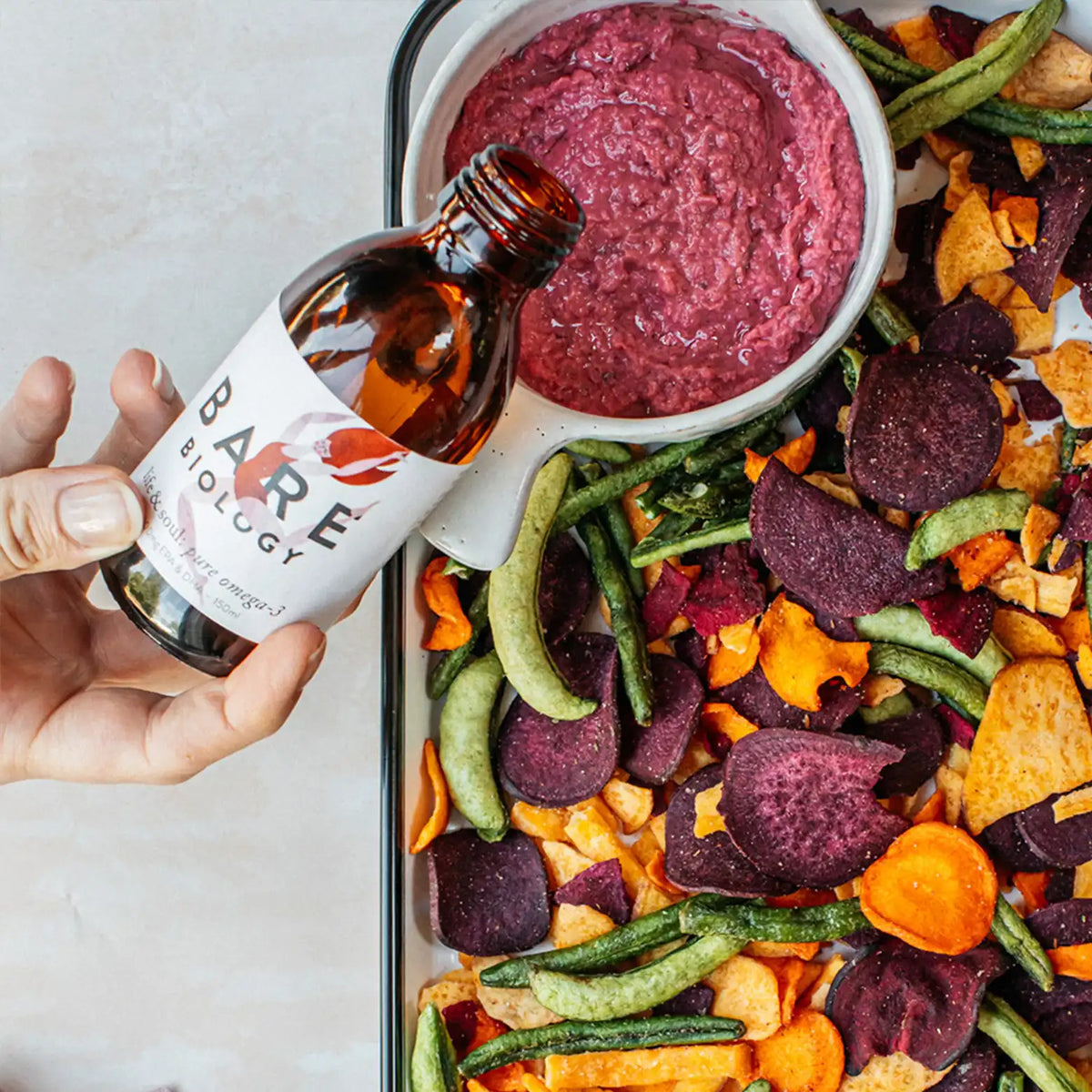 life & soul omega 3 high strength liquid being poured into dip with vegetable crisps