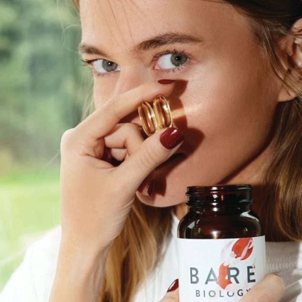 a woman holding life & soul daily omega 3 pot and capsules