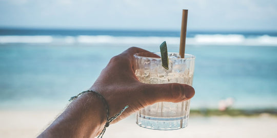 a-man-holding-a-drink-on-a-beach