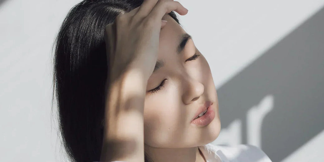 A woman holding her head in the sunlight