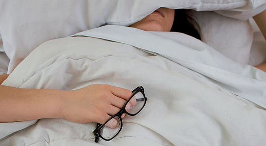 a woman in bed with glasses