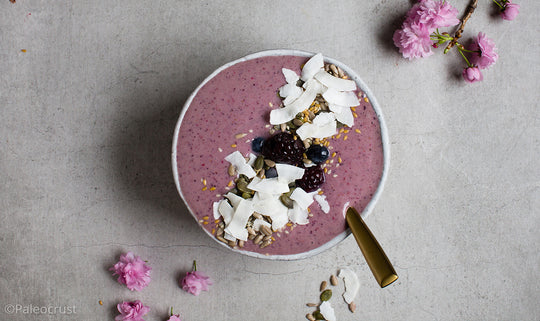 a bowl of blueberry smoothie with coconut and seeds