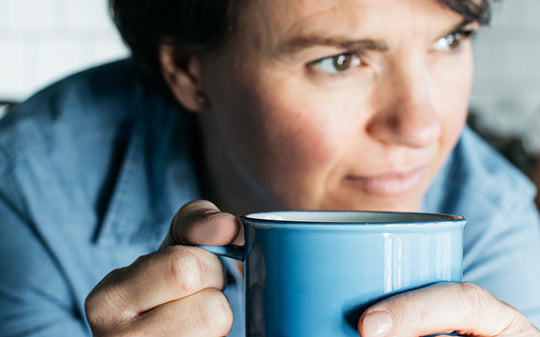a woman holding a blue mug of coffee