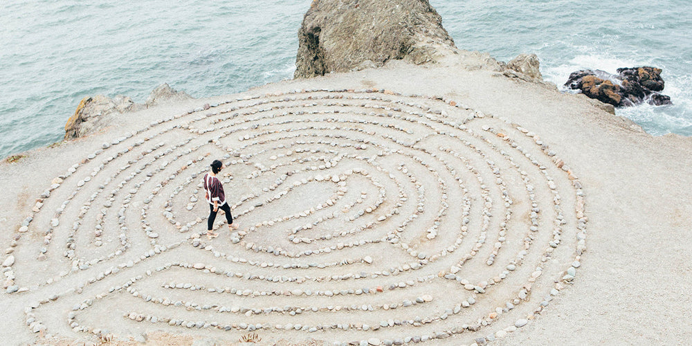 a woman walking through a pebble maze