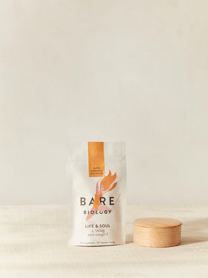 Bare Biology omega-3 pouch packaging on a neutral background next to a wooden stand 