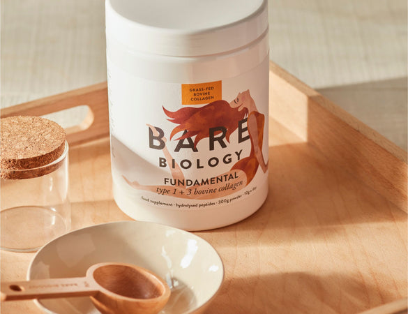 Bare Biology supplement container on a wooden tray with a bowl and bare biology scoop.