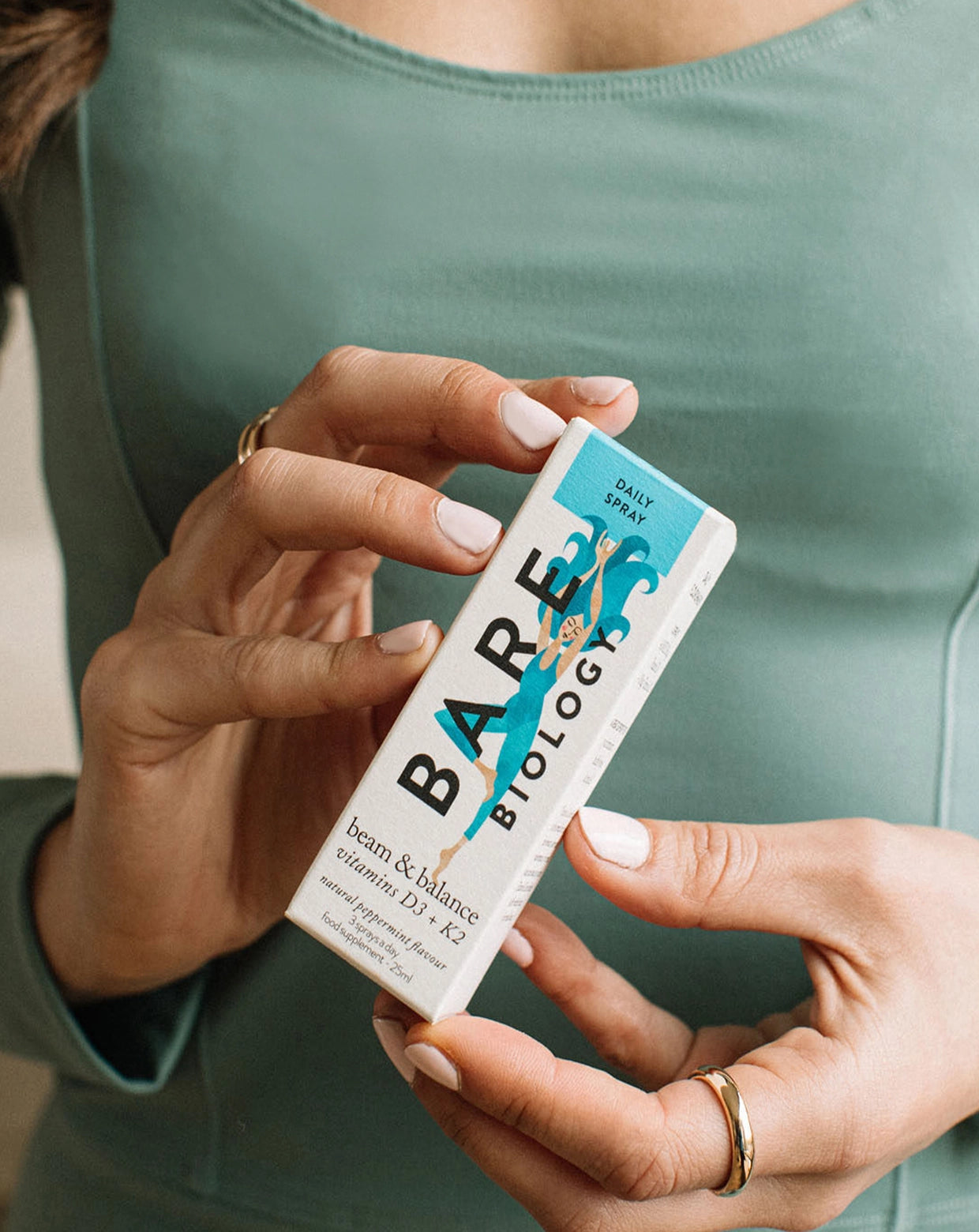 a woman holding bare biology's vitamin d3 and k2 spray