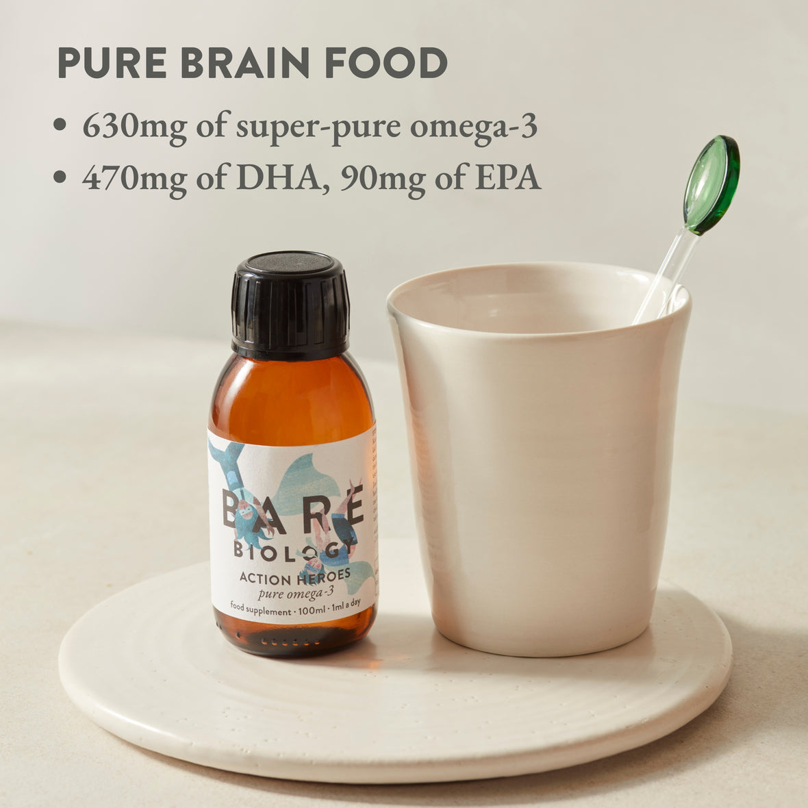 Bottle of Action Heroes Omega-3 fish oil for kids with the title 'Pure Brain Food' in writing on the top left hand corner. Supplement displayed next to a cup on a white ceramic surface