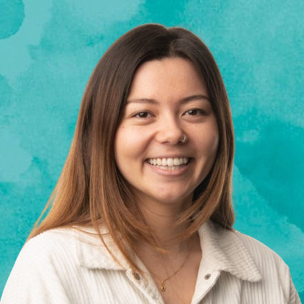 Ecommerce Specialist with shoulder-length brunette hair smiling against a teal background