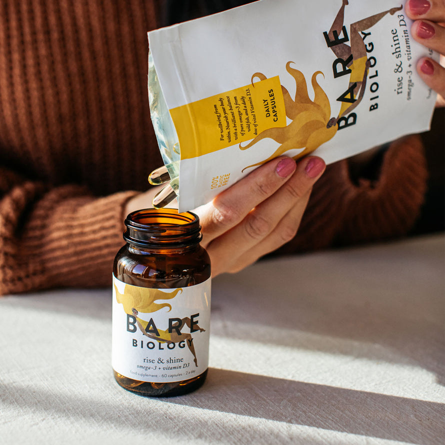 woman pouring bare biology rise and shine fish oils from pouch to jar