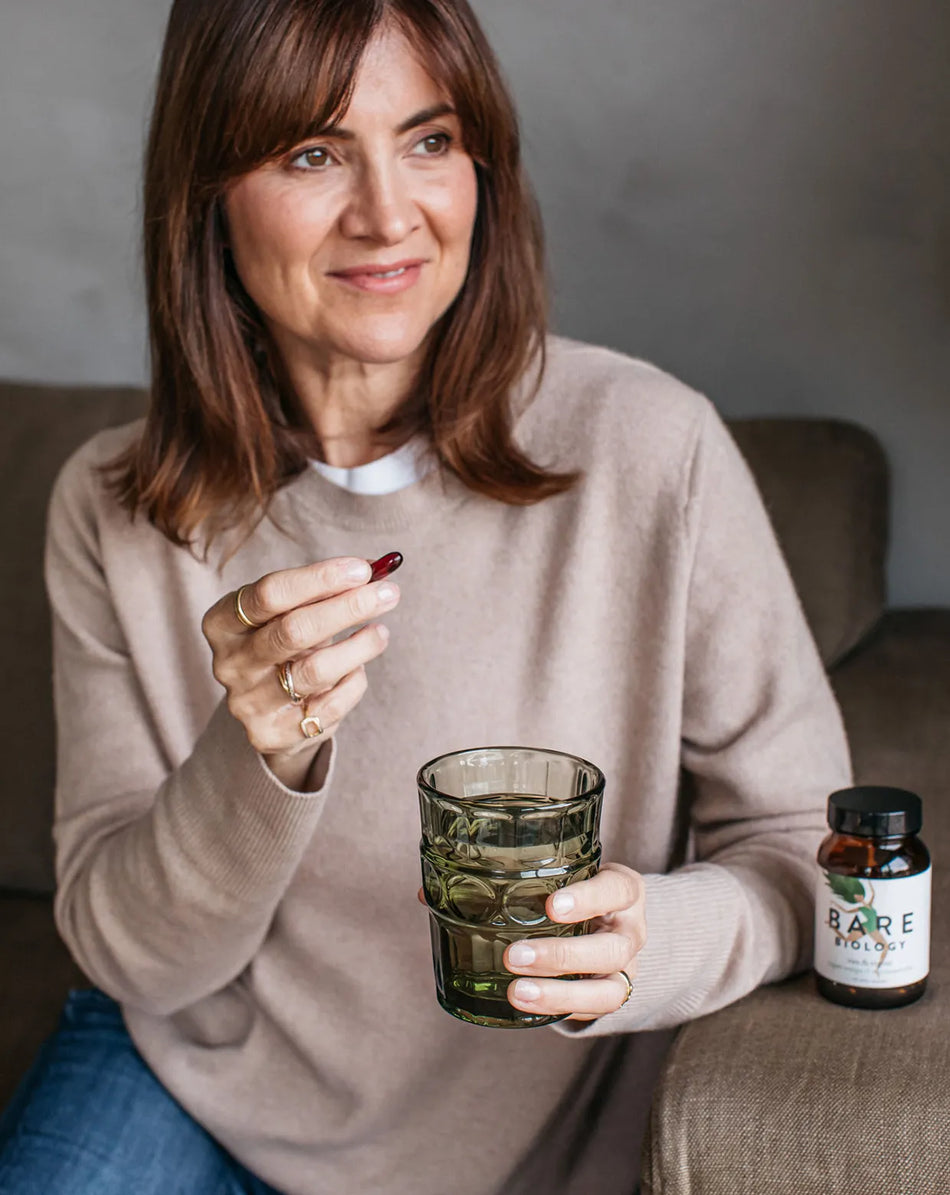 a woman holding bare biology vim & vigour vegan omega 3 and astaxanthin capsules