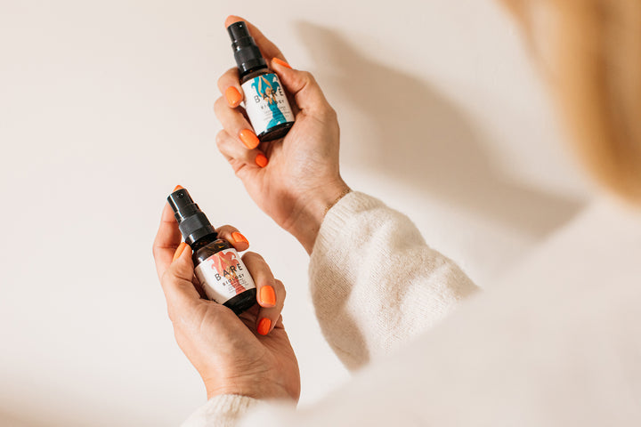 Woman holding bare biology's beam & balance vitamin d + k2 spray range