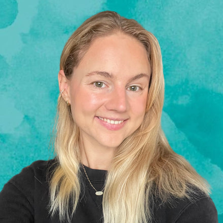 Woman with blonde hair smiling against a teal background