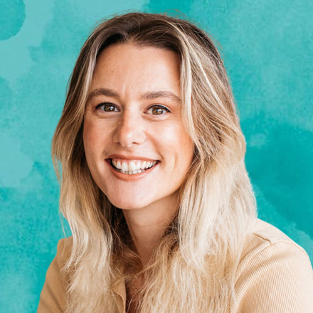 Woman with blonde hair smiling against a teal background