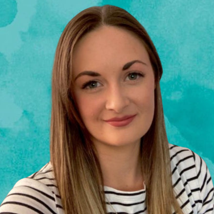 Woman with long blonde hair wearing a striped shirt against a teal background