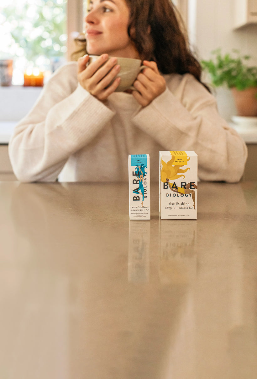 woman holding a mug sitting in front of bare biology immunity supplement range
