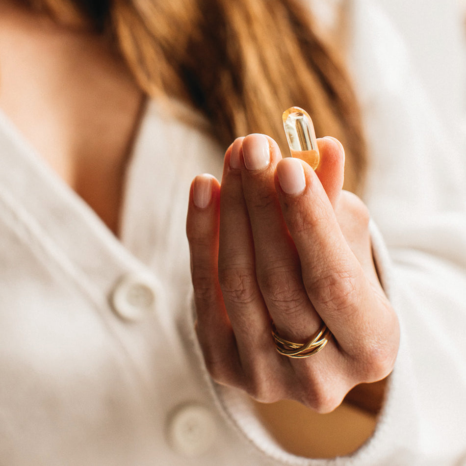 a woman holding a bare biology omega 3 daily capsule
