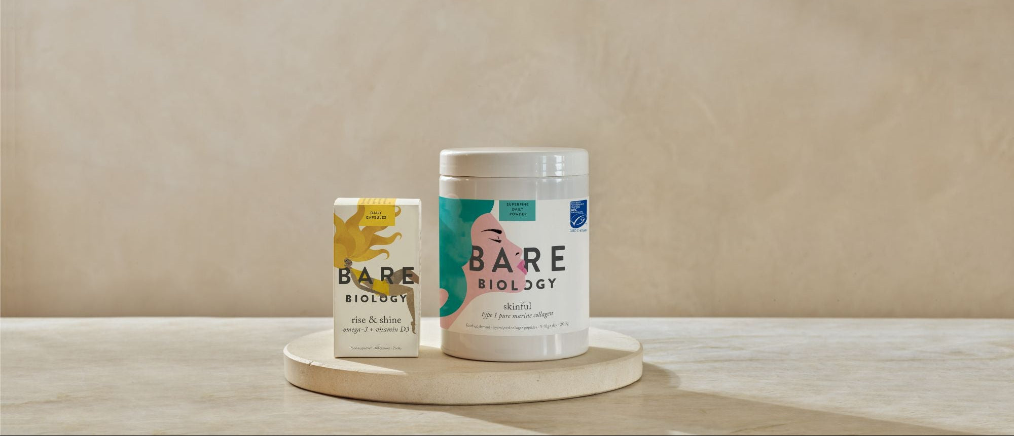Two containers of Bare Biology products on neutral stone look surface with a beige background.