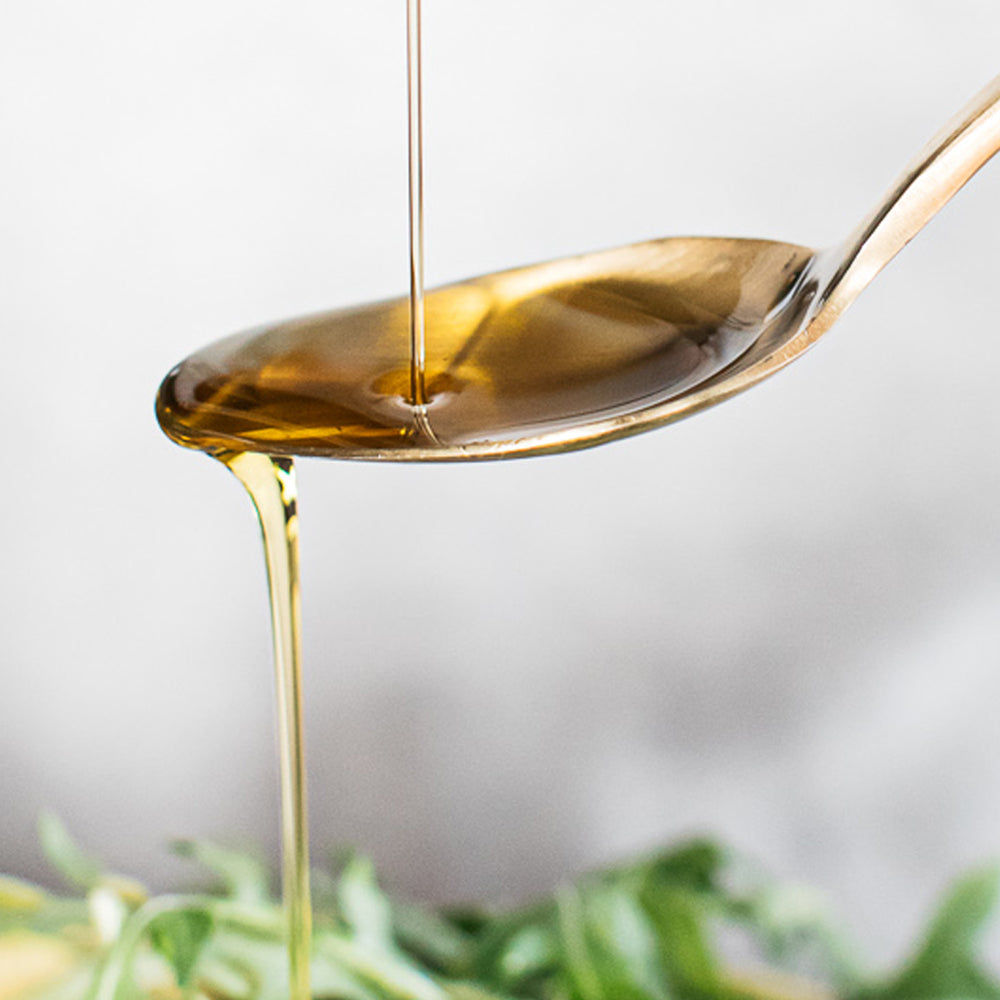 a spoon of bare biology life & soul high strength omega 3 liquid on a salad 