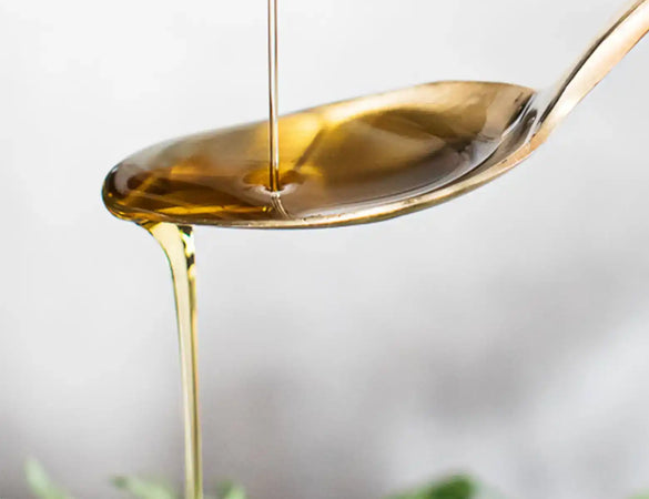 omega 3 high strength liquid on a gold spoon being poured onto a salad