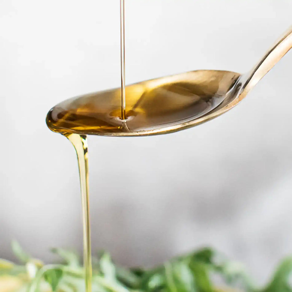 omega 3 high strength liquid on a gold spoon being poured onto a salad