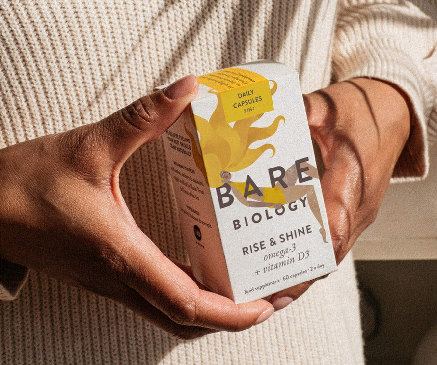 Person holding a box of Bare Biology Rise & Shine supplement
