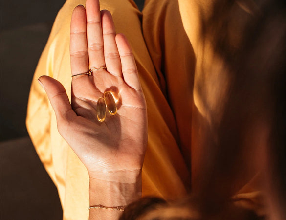 a woman sitting in the sun with bare biology omega 3 and vitamin d3 capsules