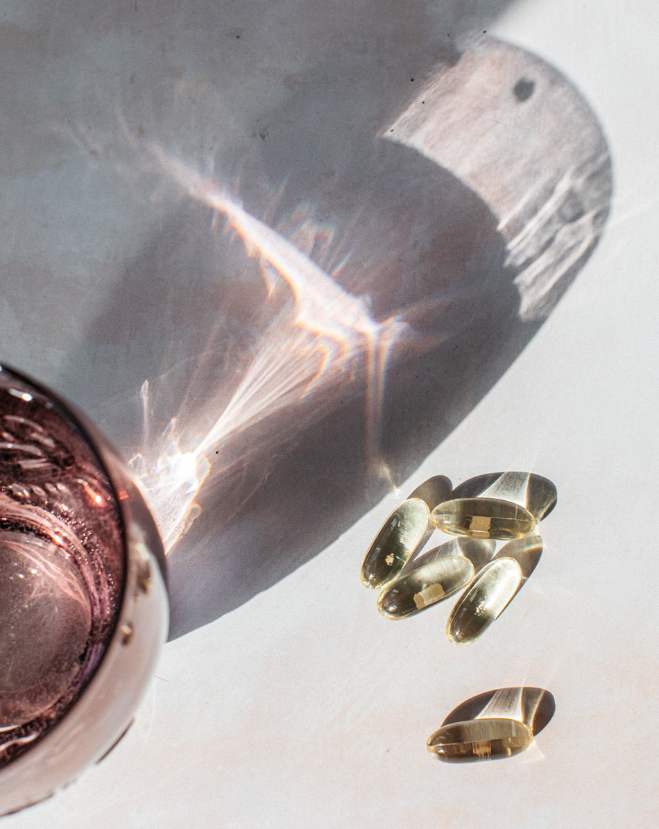 bare biology omega 3 daily capsules with a glass of water and sun reflection