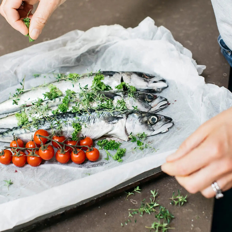 fish on a baking tray with tomatoes and herbs