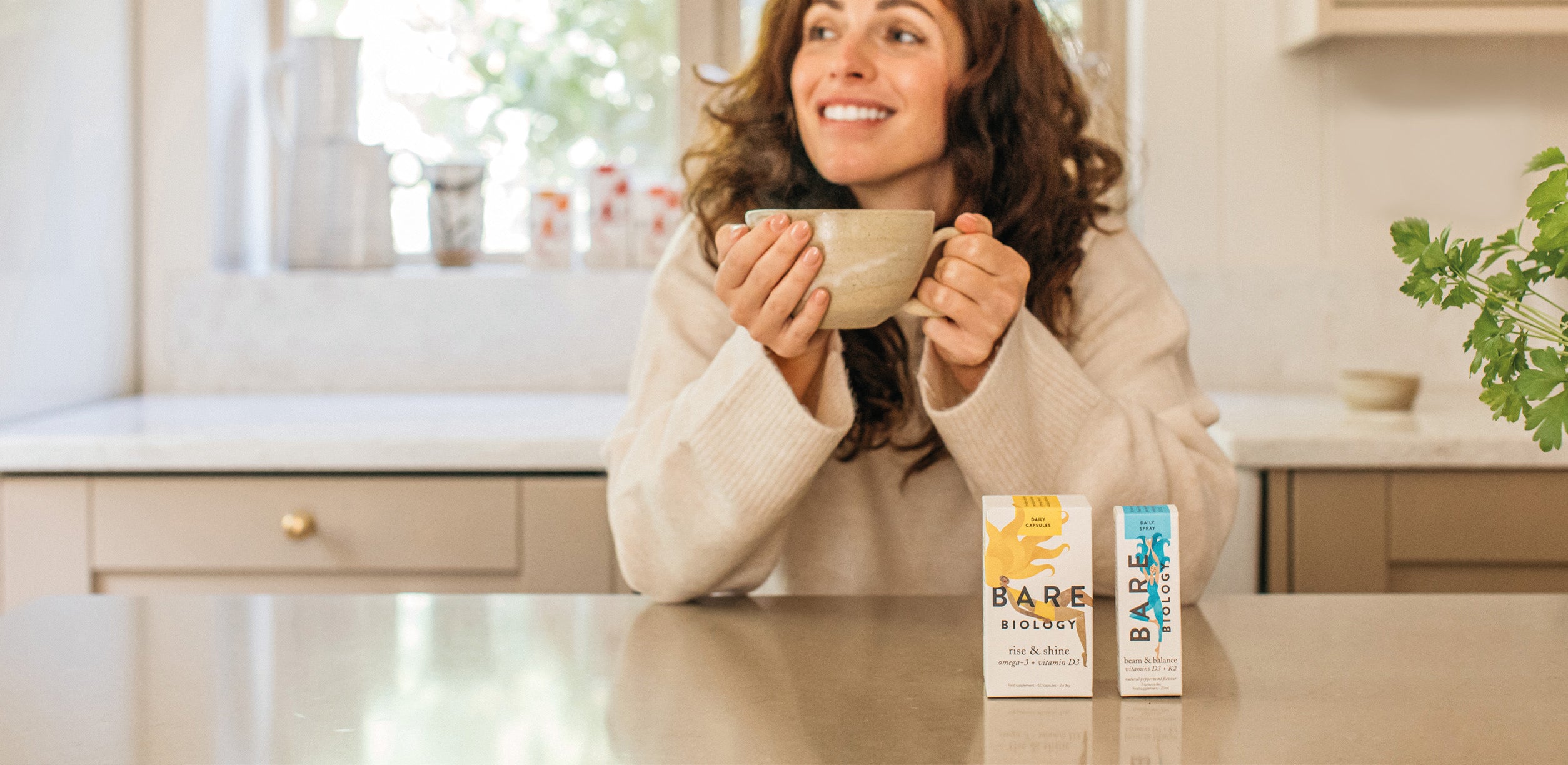 woman holding a mug at the table in front of bare biology immunity supplements