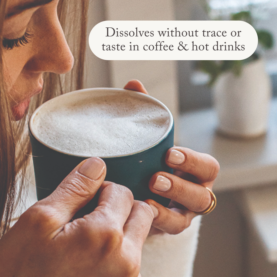 a woman having a sip of a collagen coffee with bare biology skinful marine collagen powder supplement on the window sill