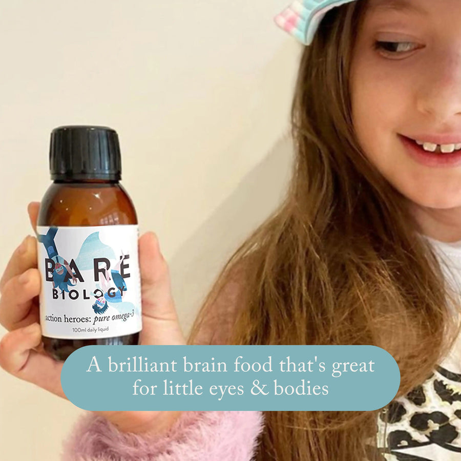 a child holding a bottle of action heroes fish oil for kids
